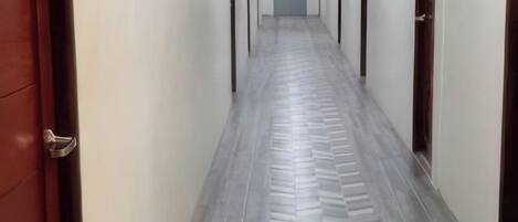 A hallway with a patterned floor and doors on either side.