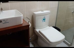 Un baño con lavamanos, inodoro y ducha blancos.
