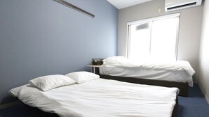 Ein Hotelzimmer mit zwei Betten, einem Fenster und einem Schreibtisch.