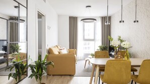 A modern living room with a sofa, dining table, chairs, and a large mirror.