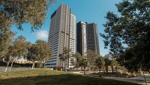 Two high-rise buildings with a park in the foreground.