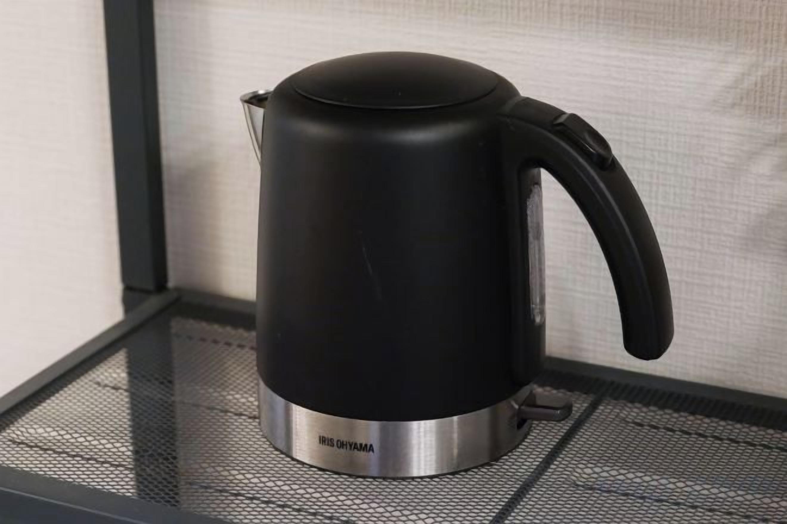 Una tetera eléctrica negra sobre una mesa de vidrio.