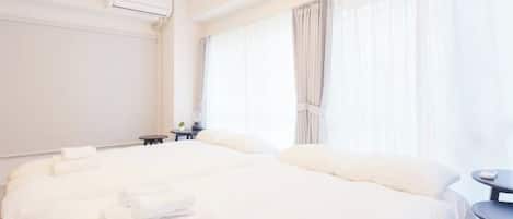 Una camera d'albergo con un letto grande, un comodino, un tavolino e una finestra con tende.