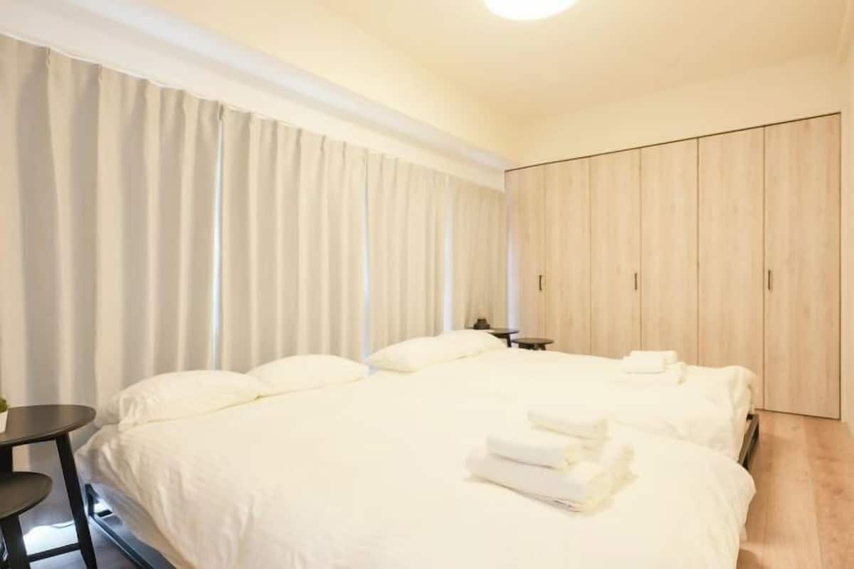 A hotel room with a large bed, a small table, a wardrobe, and a curtain.