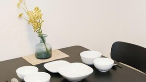 A table set with white bowls and a glass vase with yellow flowers. - Oyama Pantheon (Tokyo)