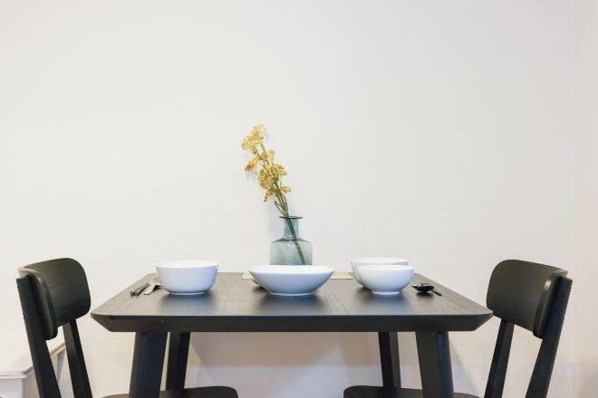 A dining table with four white bowls and a vase with yellow flowers.