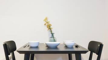A dining table with four white bowls and a vase with yellow flowers.