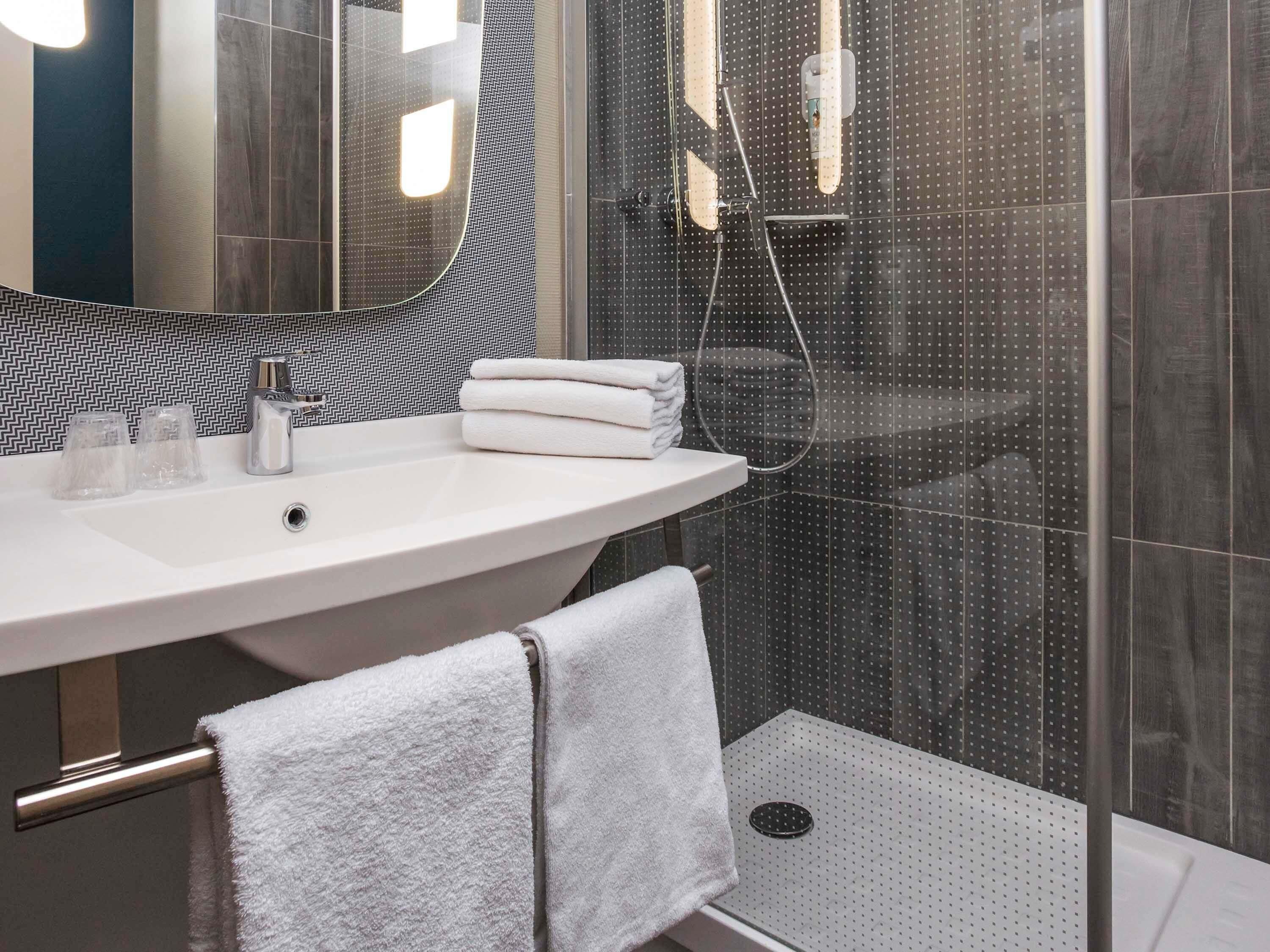 A modern bathroom with a curved sink, a glass shower enclosure, and a visible showerhead.