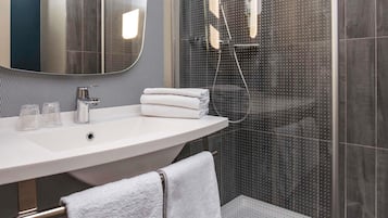 A modern bathroom with a curved sink, a glass shower enclosure, and a visible showerhead.