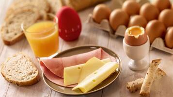 Un desayuno con pan, huevos, queso y un vaso de jugo de naranja.