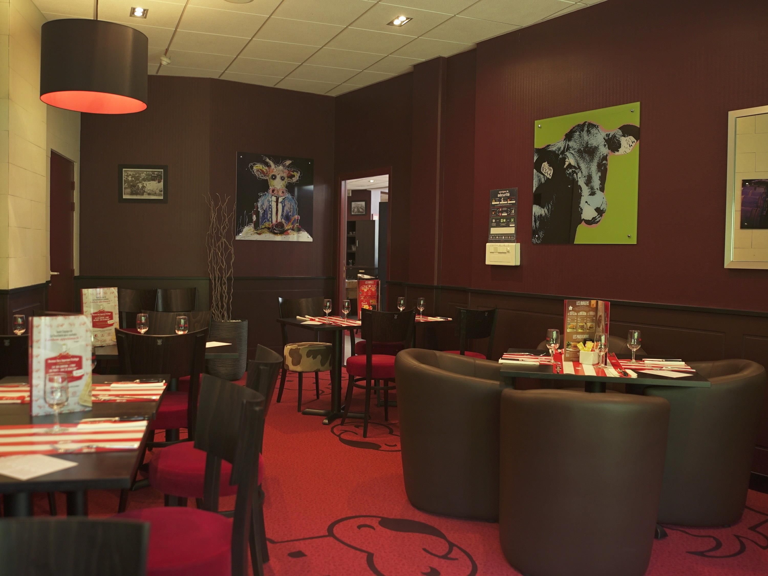Ein Restaurantinneres mit Tischen, Stühlen und Kunstwerken an den Wänden.