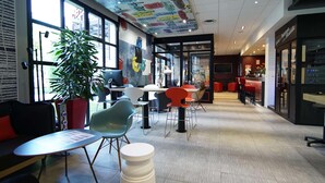 Ein modernes Interieur mit Sitzgelegenheiten, einer großen Pflanze und einer gewölbten Decke mit Schrift.