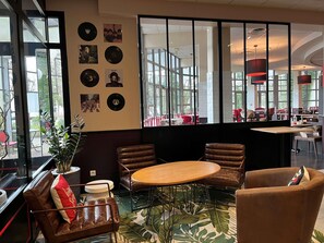 A modern interior with a round table, leather chairs, and a wall decorated with vinyl records. - Ibis Villepinte Parc Expos (Villepinte)