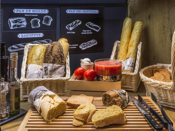 A variety of breads and pastries on a wooden table, with baskets and bottles of olive oil. - Ibis Villepinte Parc Expos (Villepinte)