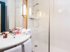 A modern bathroom with a glass-enclosed shower, a white sink, and a mirror. - Ibis Villepinte Parc Expos (Villepinte)