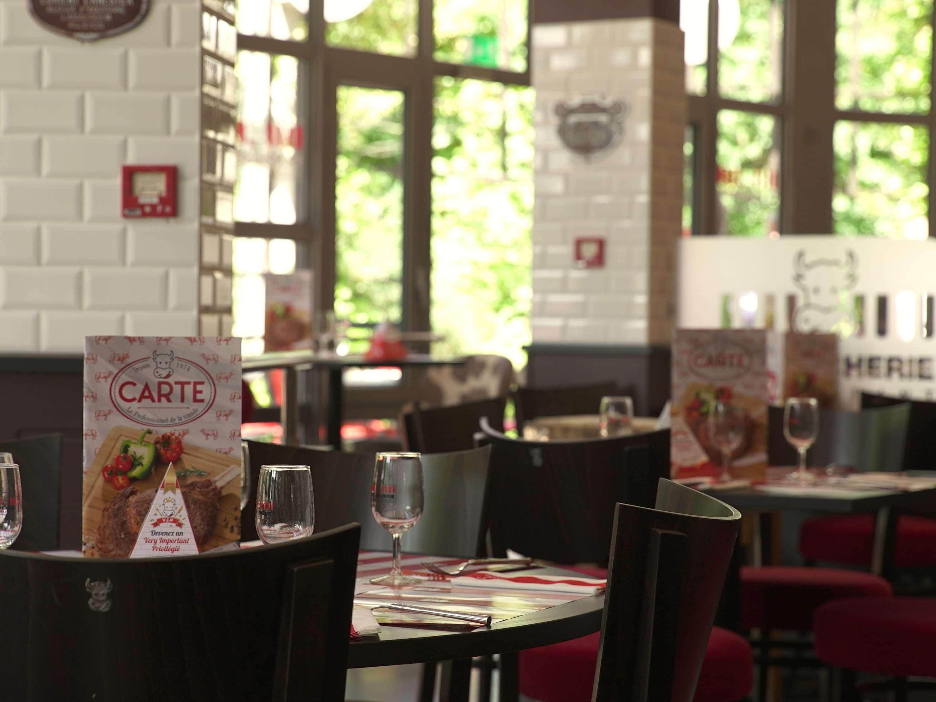 A restaurant interior with tables, chairs, menus, and a brick wall.