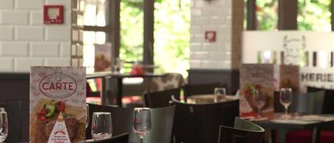 Ein Restaurantinneres mit Tischen, Stühlen, Speisekarten und einer Ziegelwand.