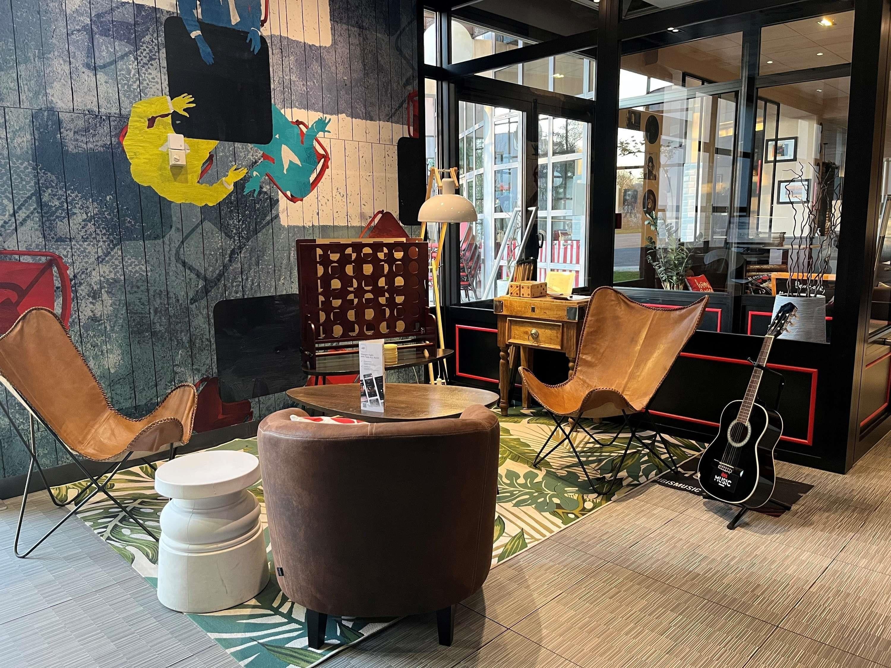 A modern interior with a seating area, a guitar, and a wall with abstract art.