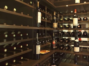 A wine cellar with shelves of wine bottles, a glass display case, and a wine rack. - Ibis Villepinte Parc Expos (Villepinte)