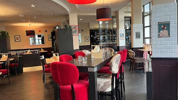 A restaurant interior with red upholstered chairs, a bar area, and a counter.