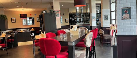 Ein Restaurantinneres mit rot gepolsterten Stühlen, einer Bar und einer Theke.