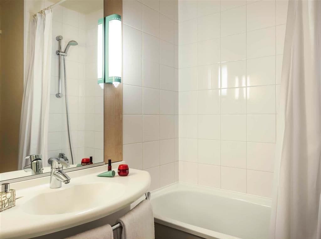 Un bagno con lavandino bianco, specchio e doccia.