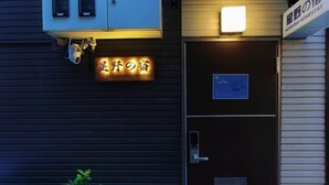 A hotel entrance with a neon sign, a security camera, and a closed door. - hoshino homestay (Osaka)