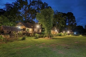 Un hôtel de style chalet en bois, doté de nombreuses chambres, d’une cour verdoyante et d’arbres en arrière-plan.