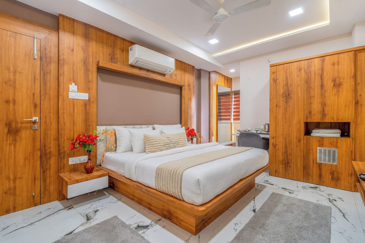 A modern bedroom with a wooden bed frame, a bedside table with a vase of flowers, and a built-in wardrobe.