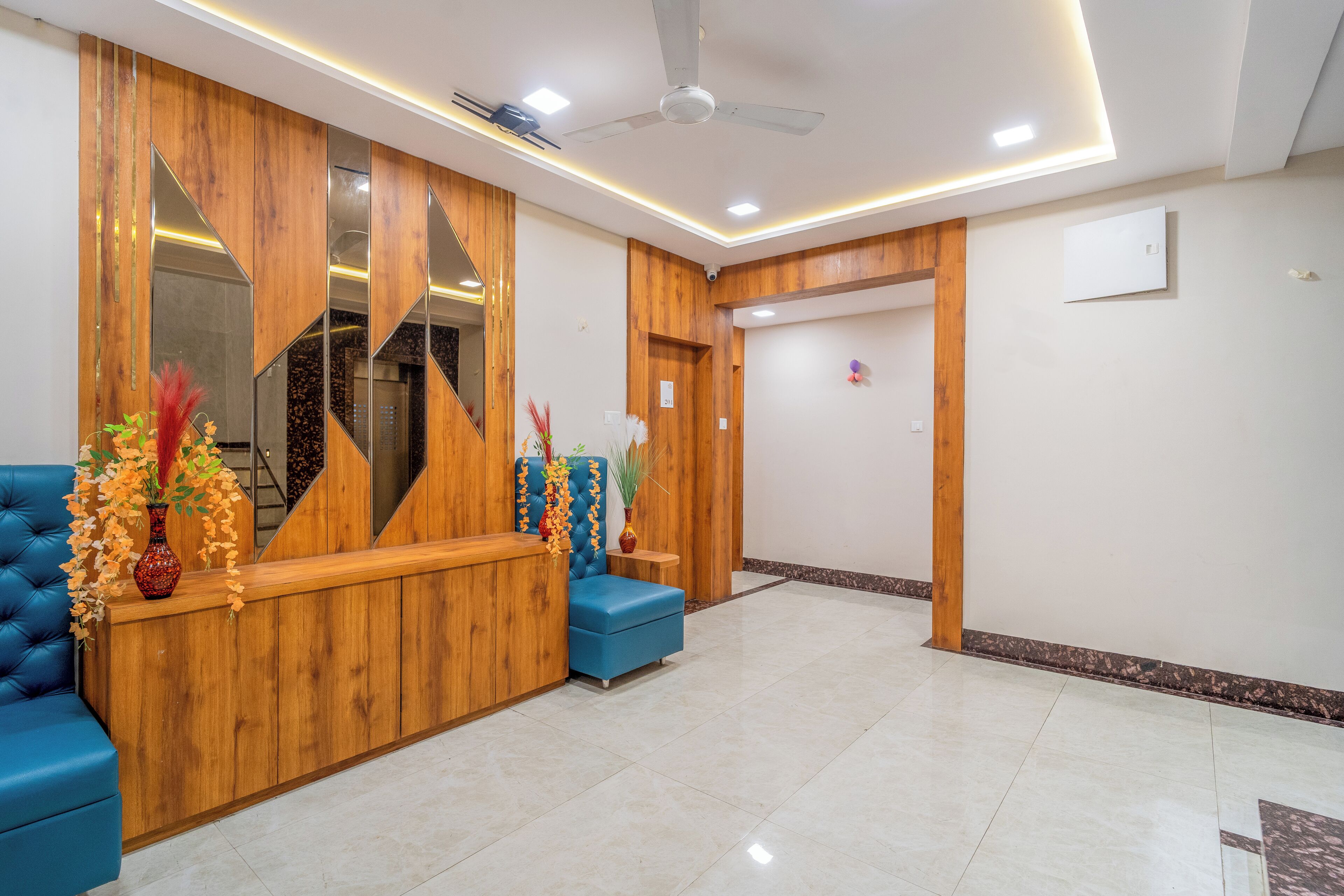 A reception area with a wooden reception desk, blue seating, and a ceiling fan.