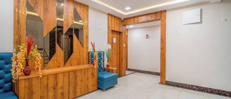 A reception area with a wooden reception desk, blue seating, and a ceiling fan.