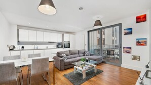 Een modern appartement met een eethoek, een woonkamer met een bank, een keuken en een balkon met uitzicht.