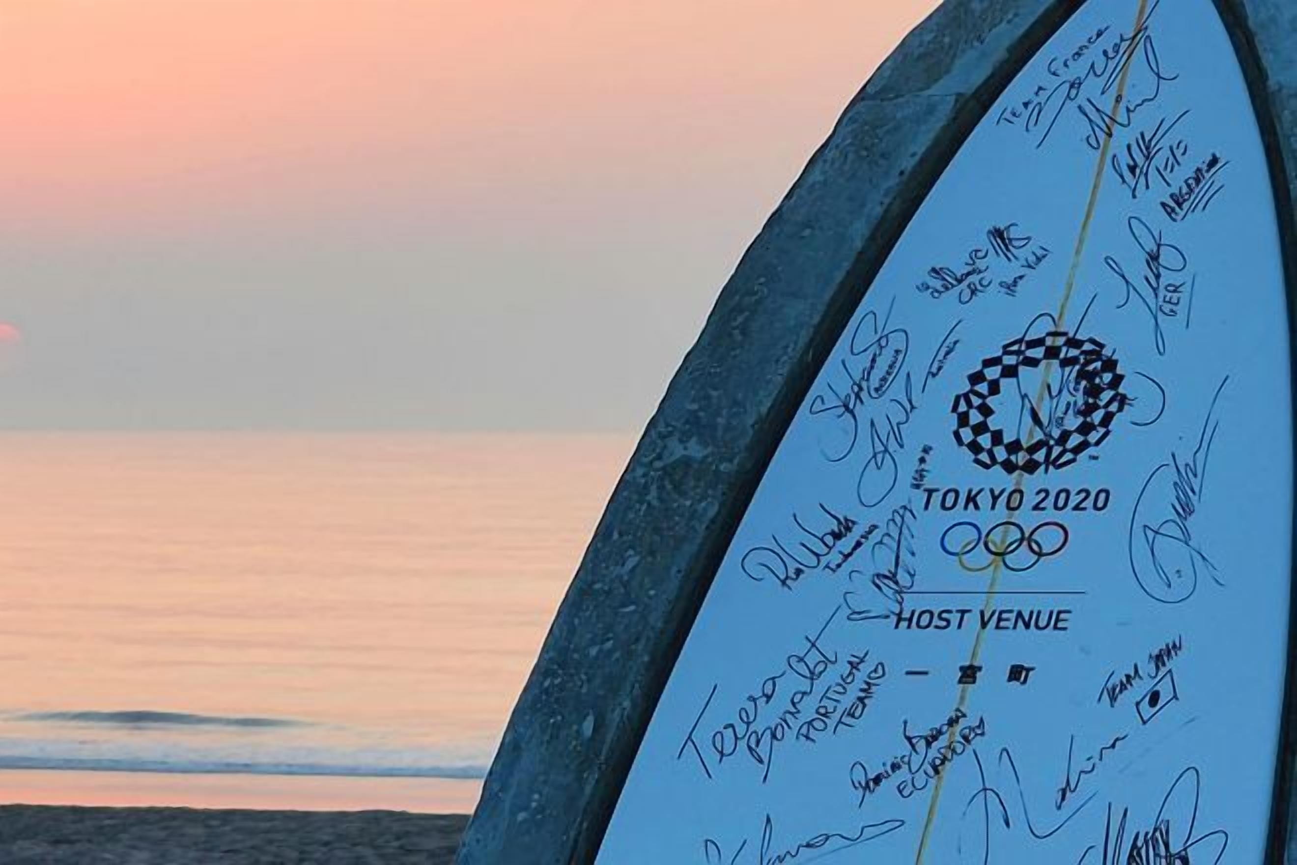 A surfboard with signatures and the Tokyo 2020 Olympics logo.
