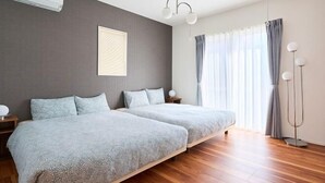 Ein modernes Schlafzimmer mit zwei Betten, einem großen Fenster mit Vorhängen, einer Stehlampe und einem Deckenventilator.