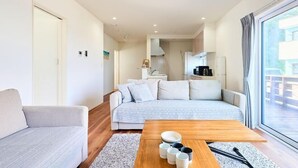 Ein modernes Wohnzimmer mit einer Couch, einem Couchtisch mit Tassen und Blick ins Freie.