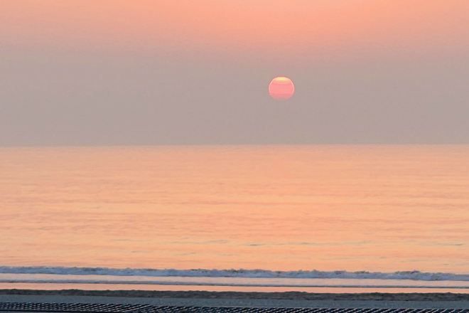 A sunset over a calm sea with a clear sky.