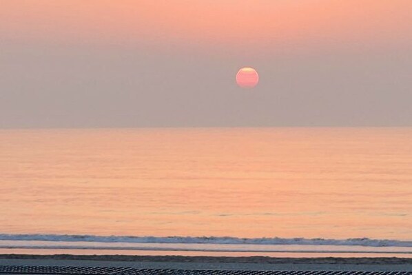 A sunset over a calm sea with a clear sky.