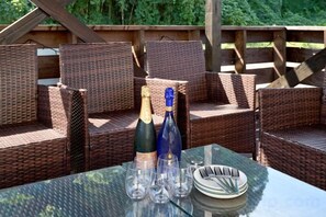 A glass table with two bottles and glasses, surrounded by wicker chairs. - KandoStay Kujyukuri SORA Terrace (Ichinomiya)