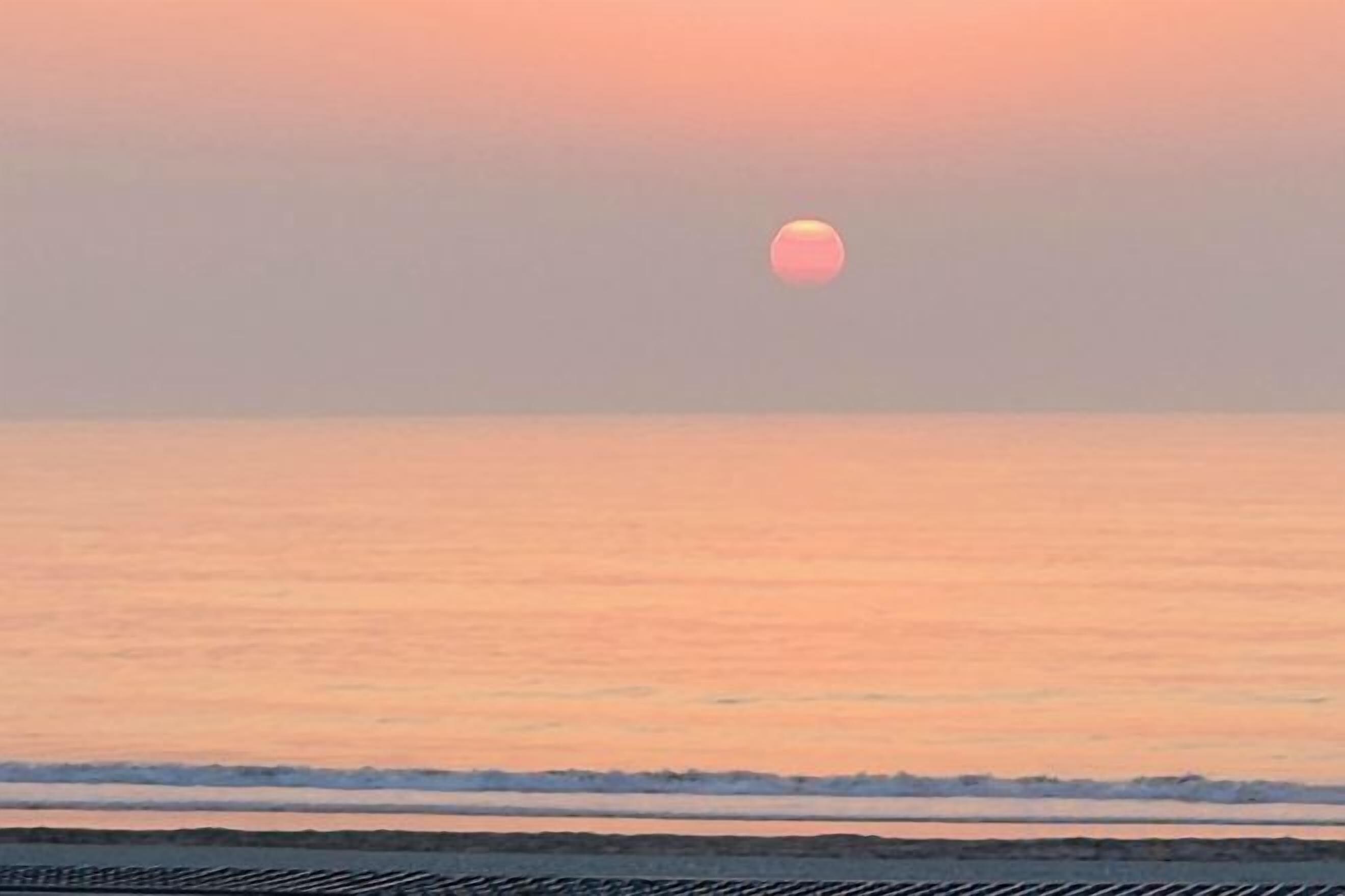 A sunset over a calm sea with a clear horizon.