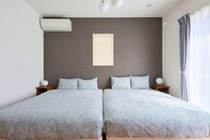 Un lit double avec une couvre-lit à motifs, une table de chevet avec une lampe et une fenêtre avec des rideaux.