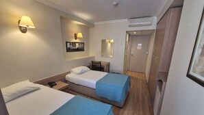 A hotel room with two single beds, a desk, a chair, a small table, and a mirror. - Haydarpasa Hotel (Istanbul)
