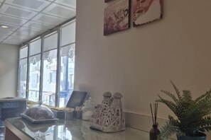A reception area with a counter, a decorative house model, a potted plant, and framed artwork on the wall. - Haydarpasa Hotel (Istanbul)