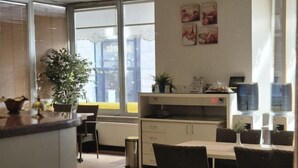 A modern kitchen with a dining area, featuring a large window, a potted plant, and a small island with a sink. - Haydarpasa Hotel (Istanbul)