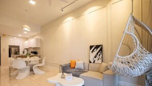 A modern living room with a sofa, a hanging chair, and a dining area with white furniture. - ELEMENT BY FEEL HOME(The elements@Ampang) (Kuala Lumpur)