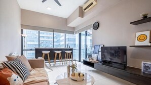 A modern living room with a sofa, coffee table, TV, and a balcony with a bar area. - ELEMENT BY FEEL HOME(The elements@Ampang) (Kuala Lumpur)