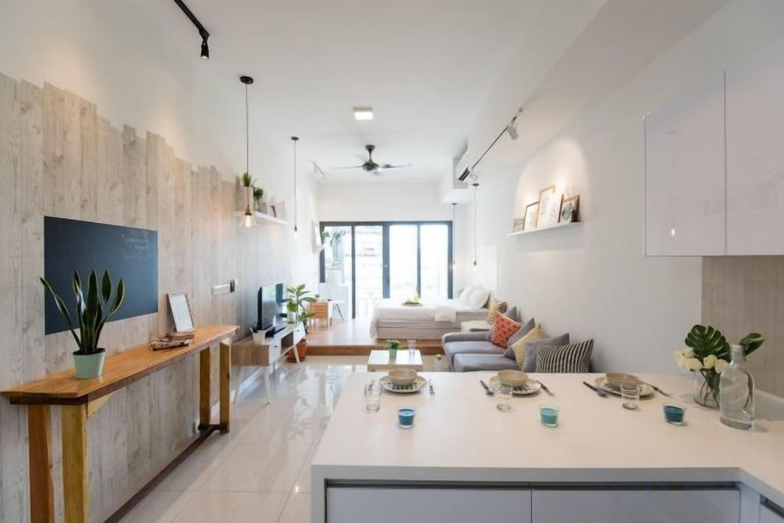 A modern kitchen with a central island, a dining area with a sofa, and a view of the living room.