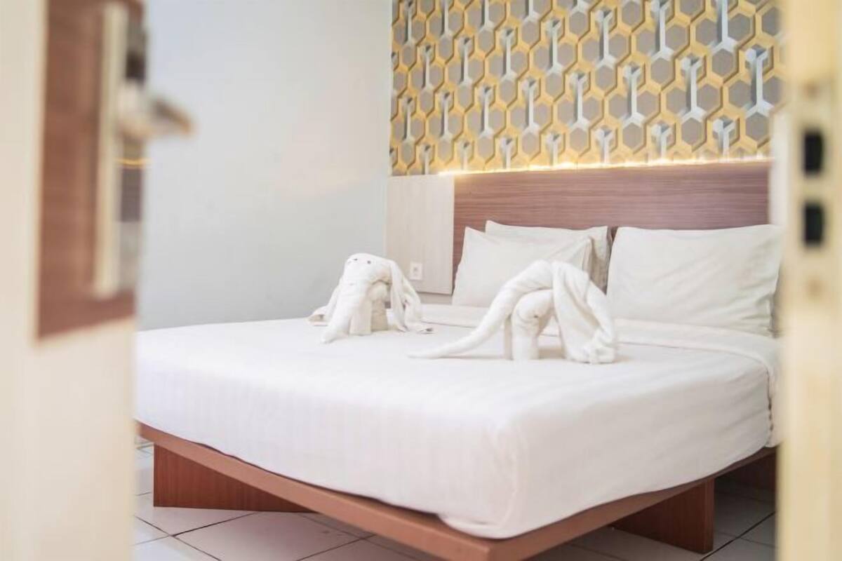 Une chambre d’hôtel avec un lit, une tête de lit et un mur décoré d’un motif.