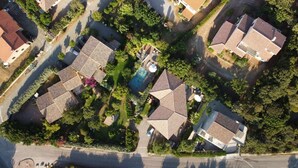 An aerial view of a residential area with multiple houses, a swimming pool, and well-maintained gardens.