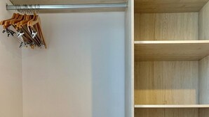 A walk-in closet with wooden shelves and a metal rod for hanging clothes.
