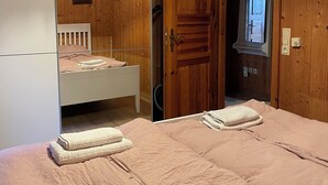 A wooden room with a bed, a small table, and a door leading to another room. - Schönblick B8 House · Mountain Charm with a View of Nature (Schöfweg)